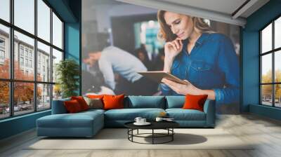 Beautiful businesswoman holding tablet in modern office Wall mural