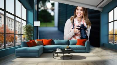 Beautiful smiling young woman photographs on camera Wall mural