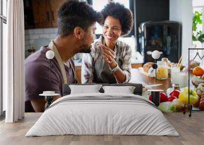 Beautiful young couple cooking healthy food together at home. Having fun in the kitchen. Wall mural