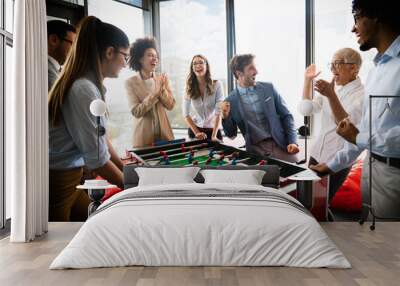 Business people having great time together.Colleagues playing table football in modern office Wall mural