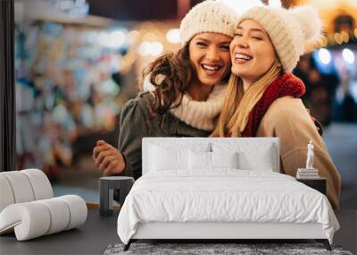 Cheerful young women friends at christmas time are having fun and shopping presents for their family Wall mural