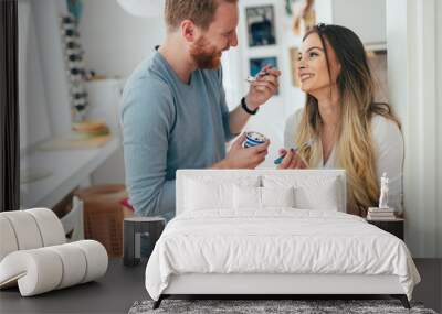 Couple having fun and laughing at home while eating ice cream Wall mural