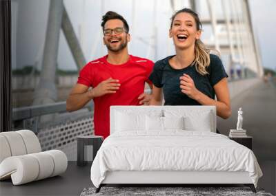 Early morning workout. Happy couple running across the bridge. Living healthy lifestyle. Wall mural