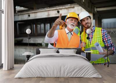 Engineer, foreman and worker discussing in building construction site Wall mural