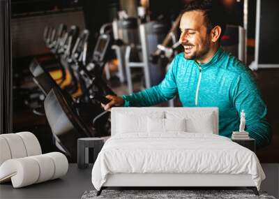 Fit happy man exercising at the gym on a machine Wall mural