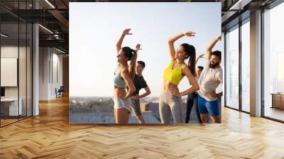 Group of happy fit friends exercising outdoor in city Wall mural