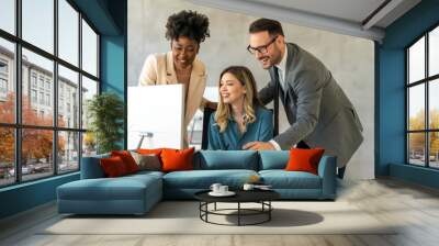 Group of happy multiethnic business people in formal wear gathered around computer in office Wall mural