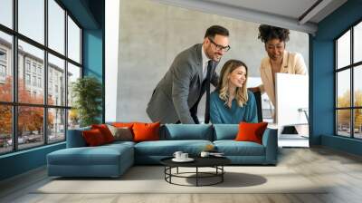 Group of happy multiethnic business people in formal wear gathered around computer in office Wall mural