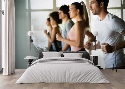 Group of young people running on treadmills in modern sport gym Wall mural