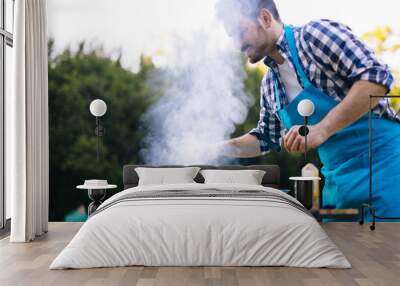 Handsome male preparing barbecue Wall mural