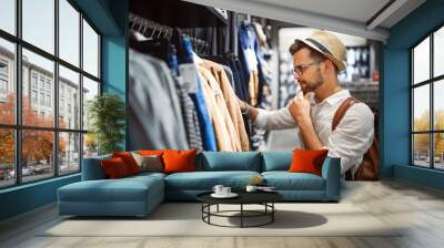 Handsome man shopping for new clothes in store Wall mural