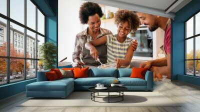 Happy african american family preparing healthy food in kitchen, having fun together on weekend Wall mural