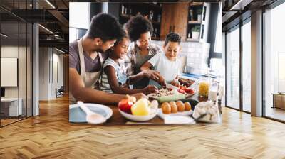 Happy african american family preparing healthy food together in kitchen Wall mural