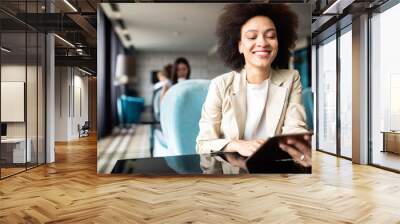 Happy black businesswoman using tablet computer in coffee shop Wall mural