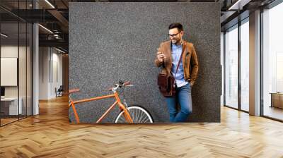 Happy businessman outside of office in urban. Young caucasian man holding smartphone for business work. Wall mural