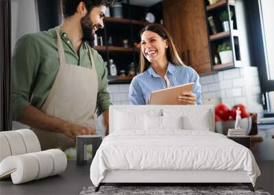 Happy couple cooking together in their kitchen Wall mural