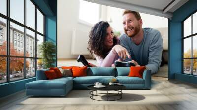 Happy couple playing video games at home Wall mural