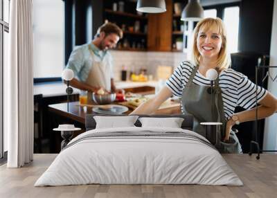 Happy couple preparing food in the kitchen Wall mural