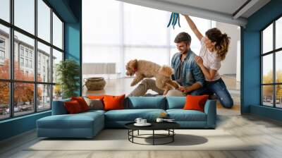 Happy family playing with their dog at home. People animal pet love concept Wall mural