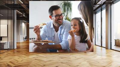 Happy family sharing pizza together at home Wall mural