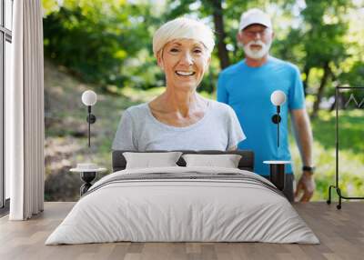 Happy fit senior couple exercising in park Wall mural