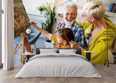 Happy grandparents and granddaughter drawing, painting together Wall mural