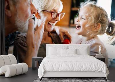 Happy grandparents playing with their little cute granddaughter Wall mural