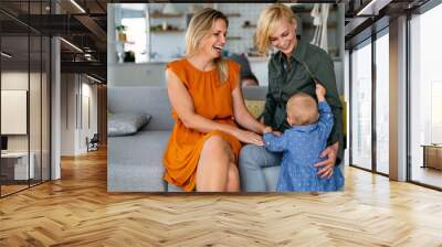 Happy lesbian female couple with her little child at home Wall mural