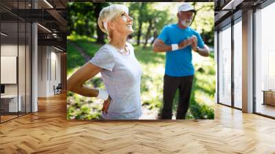 Happy mature couple stretching during running in the park Wall mural