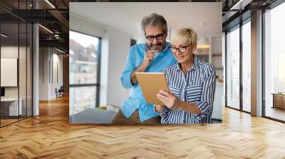 Happy smiling mature couple using digital tablet at home Wall mural