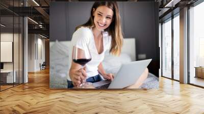 Happy woman using a laptop searching online on the bed at home Wall mural