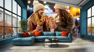 Happy women friends enjoying christmas market and having fun together outdoors. Wall mural