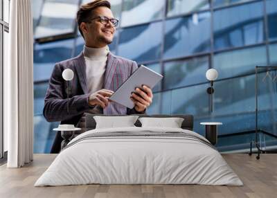 Happy young business man with tablet at work in modern urban background Wall mural