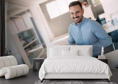 Happy young businessman holding tablet in office Wall mural