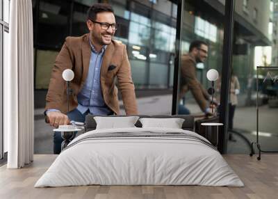 Happy young stylish businessman going to work by bike Wall mural