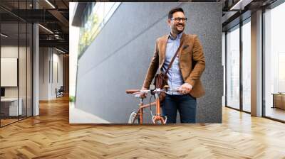 Happy young stylish businessman going to work by bike Wall mural