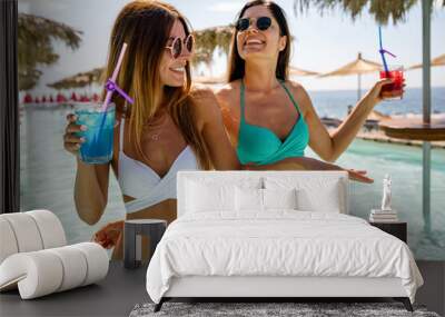 Happy young women friends enjoying summer vacation on the beach. People travel holiday fun concept Wall mural