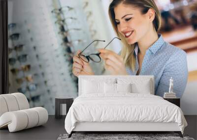 health care, eyesight and vision concept - happy woman choosing glasses at optics store Wall mural