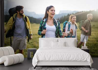 Hiking with friends is so fun. Group of young people with backpacks walking together Wall mural