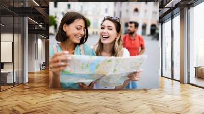 Holidays, travel, friends and tourism concept. Beautiful girls looking into tourist map in the city Wall mural