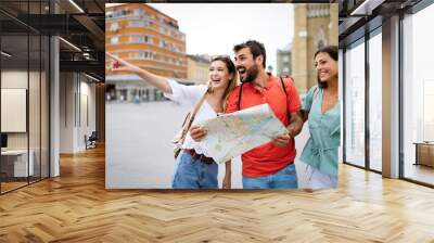 Holidays, travel, friends and tourism concept. Happy friends looking into tourist map in the city Wall mural