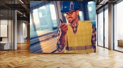 Male architect communicating on walkie-talkie at site Wall mural