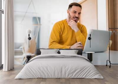 Man working at home on laptop computer Wall mural