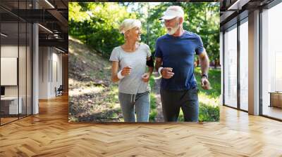 Mature couple jogging and running outdoors in city Wall mural