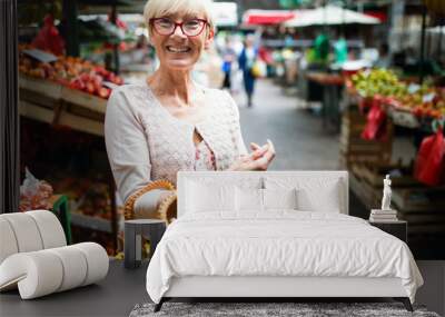 Mature woman buying vegetables at farmers market Wall mural