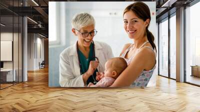 Pediatrician doctor medical examining little smiling baby, held by mother Wall mural