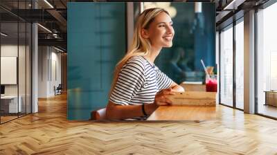 Portrait of a healthy young happy woman drinking a juice in cafe Wall mural