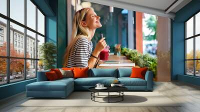 Portrait of a healthy young happy woman drinking a juice in cafe Wall mural