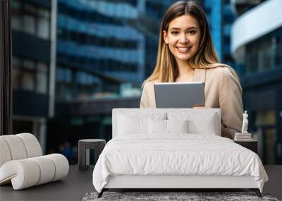 Portrait of a successful business woman using digital tablet in front of modern business building Wall mural