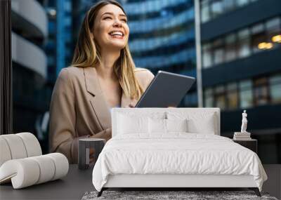 Portrait of a successful business woman using digital tablet in front of modern business building Wall mural